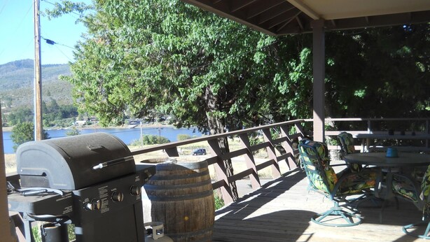 Un espace extérieur abrité comprenant un barbecue, une bouteille de gaz et un tonneau en bois.
