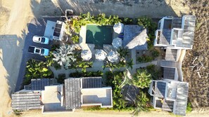 Vista aérea de um resort com piscina, áreas de descanso e várias acomodações no estilo bangalô.