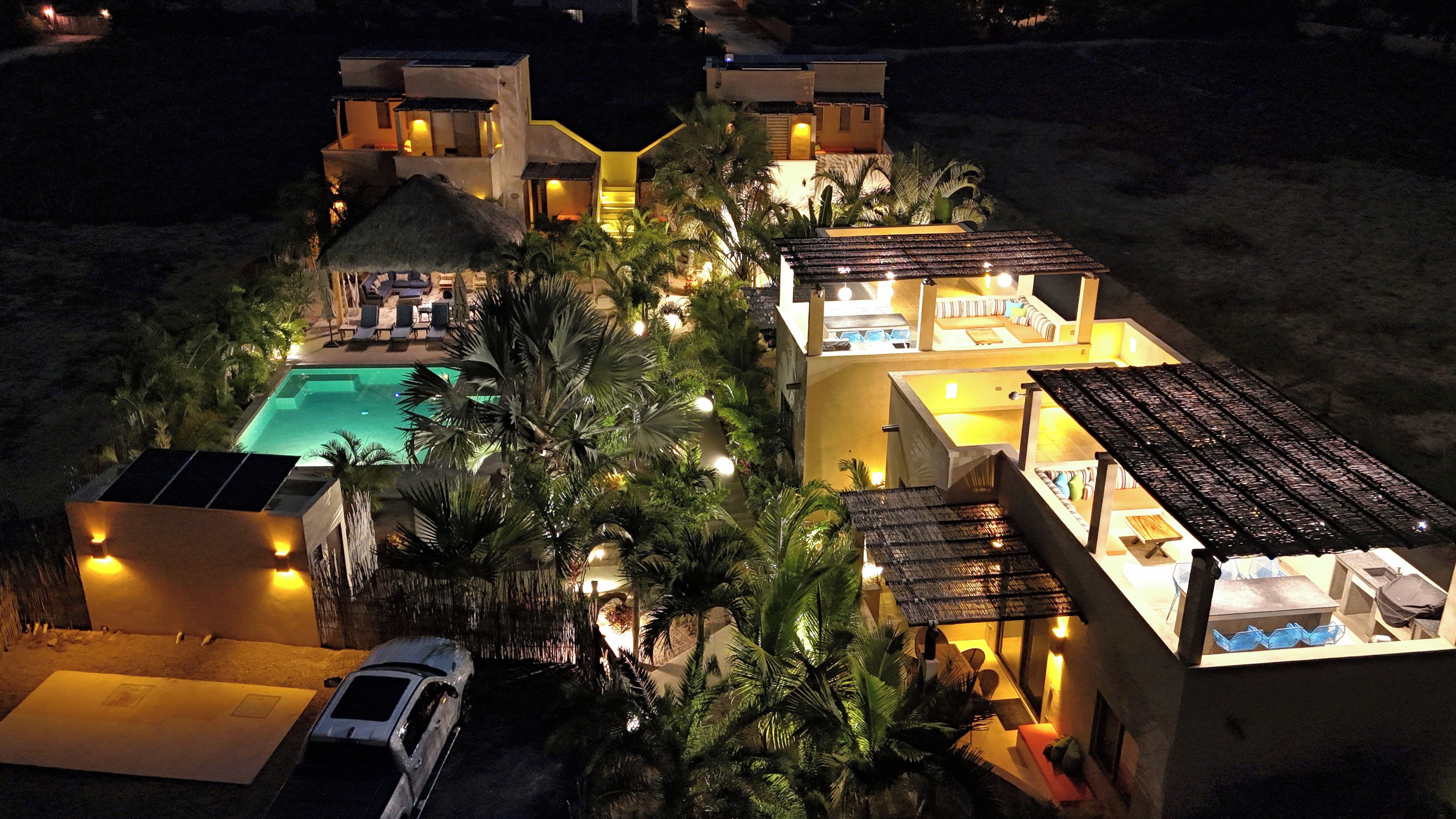 Um resort com piscina, vários quartos de hóspedes e um carro estacionado na frente.