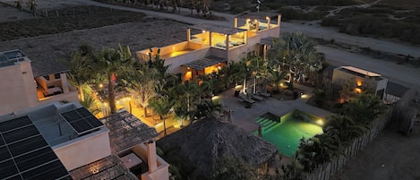 A resort with multiple buildings, a swimming pool, and a view of the ocean.