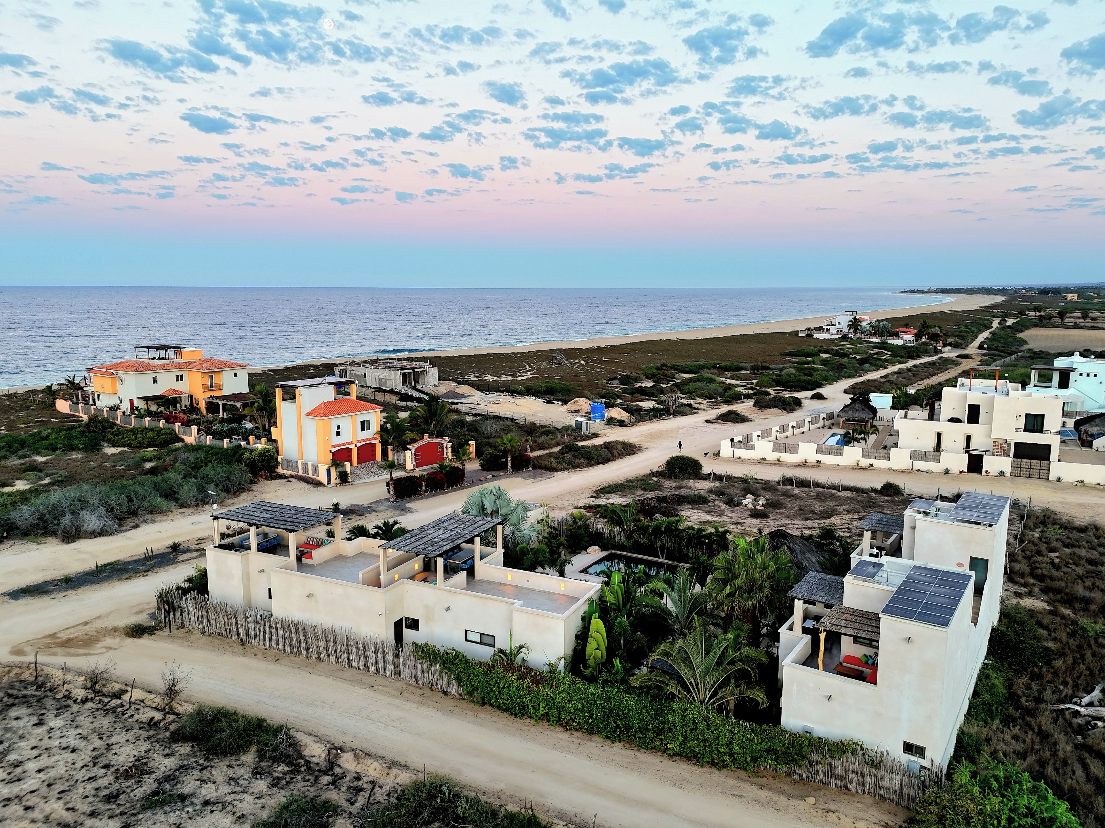 A coastal residential area with houses, a beach, and a clear sky.