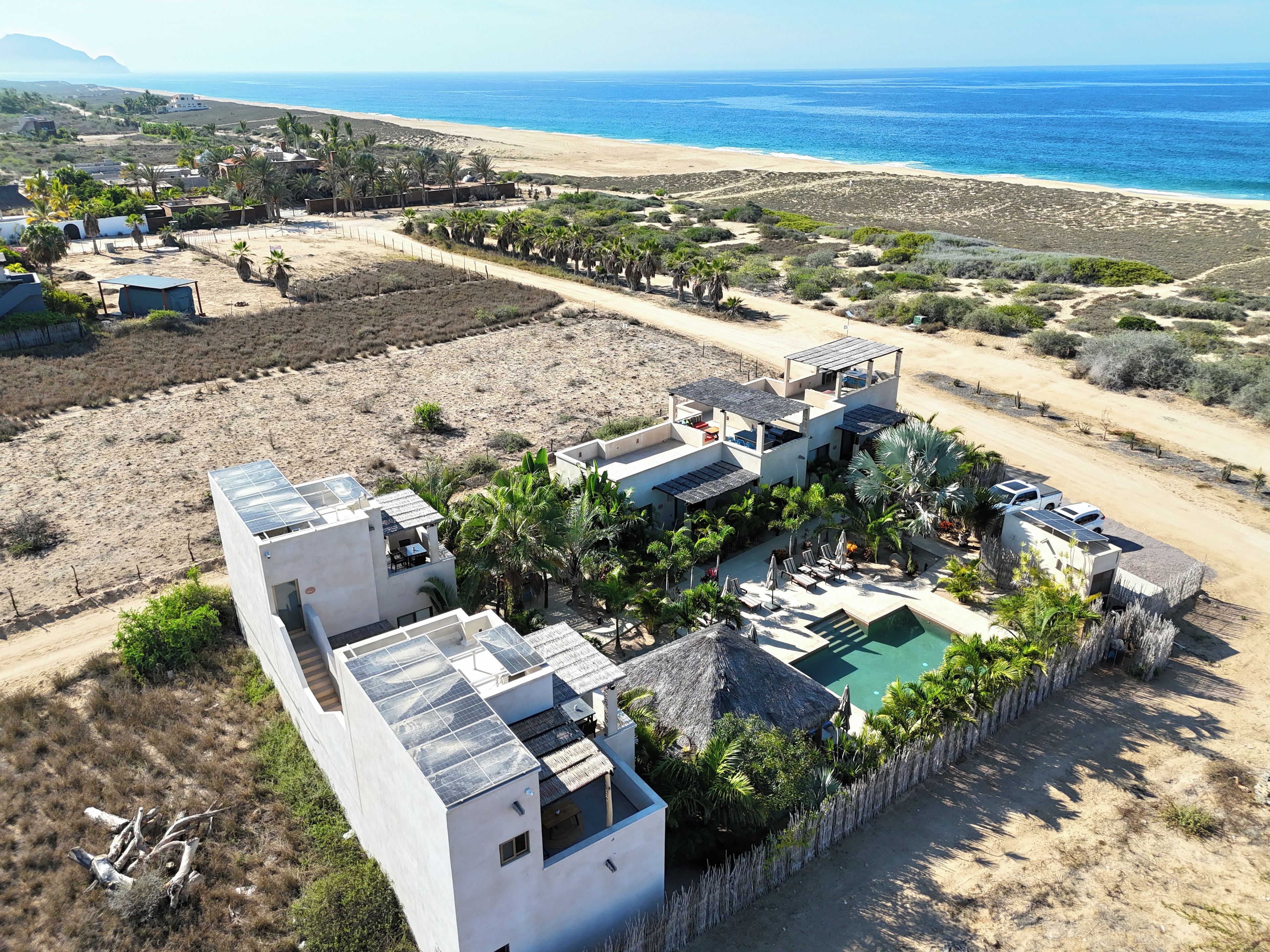 A coastal property with multiple buildings, a swimming pool, and a beach view.