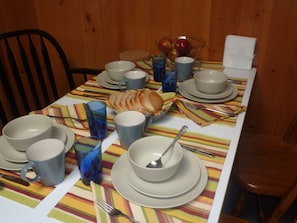 A dining table set with plates, bowls, cups, and a glass of water. - All Season Camp for Your Adirondack Adventures, 5 miles to Whitetace Mountain (Wilmington)