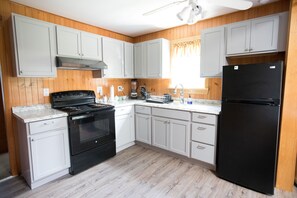 A kitchen with white cabinets, a black stove, and a black refrigerator.