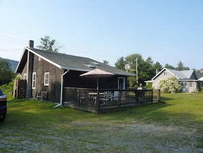 A wooden house with a covered porch and a fenced yard. - All Season Camp for Your Adirondack Adventures, 5 miles to Whitetace Mountain (Wilmington)