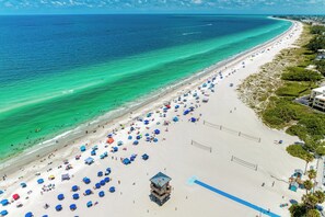 A beach with numerous umbrellas, a lifeguard tower, and a clear view of the ocean. - Across the street from the Beach, restaurants, free wifi. (Holmes Beach)