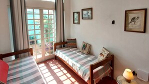 A room with a bed, a chair, a table, a ceiling fan, and a window with curtains. - JUQUEHY MIDDLE OF THE BEACH, 80 METERS FROM THE SEA. (São Sebastião)