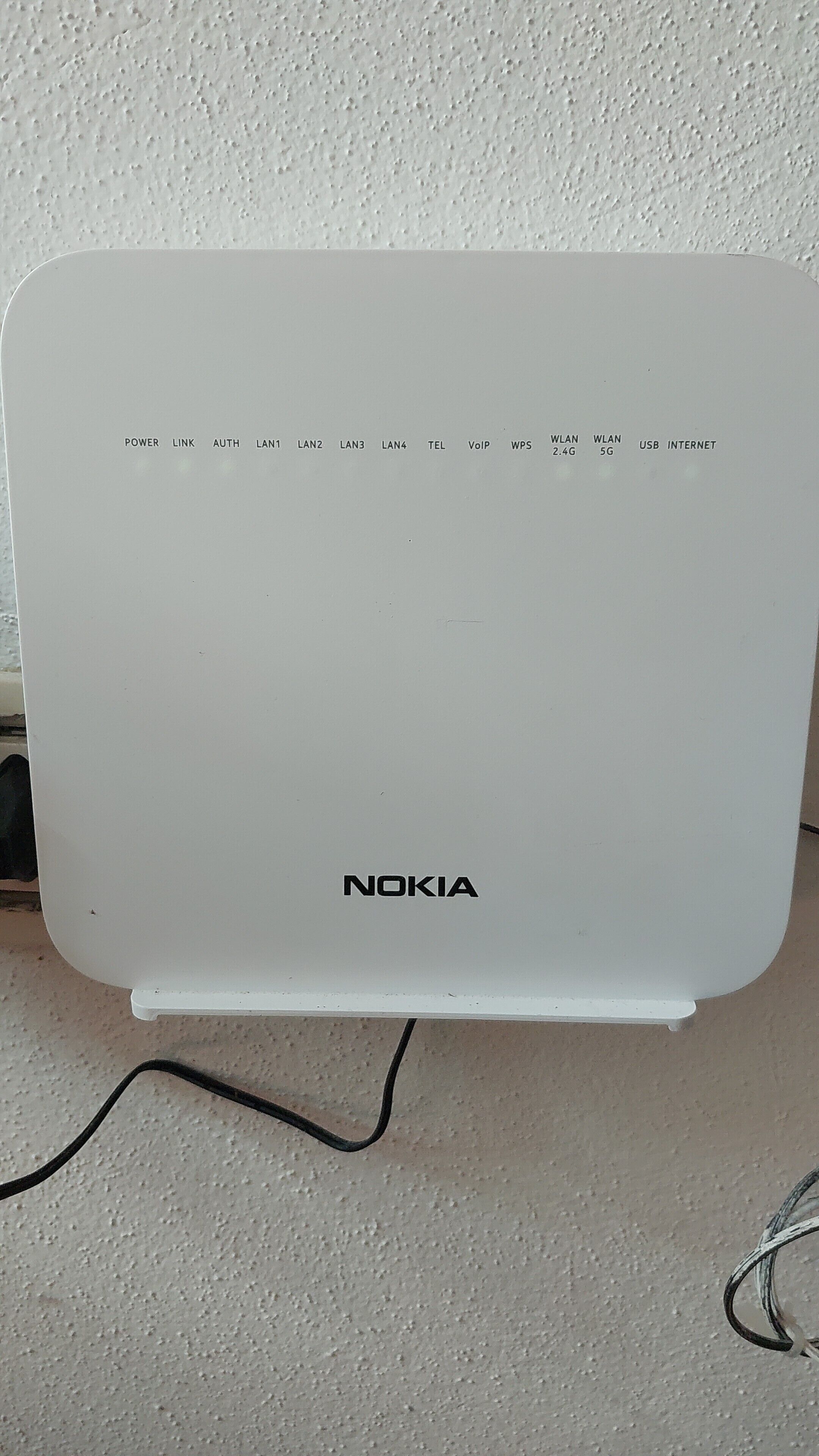 A white Nokia device with a power cord plugged in, placed on a textured surface.