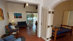 A living room with a sofa, a chair, and a bed. There is a door leading to another room. - JUQUEHY MIDDLE OF THE BEACH, 80 METERS FROM THE SEA. (São Sebastião)