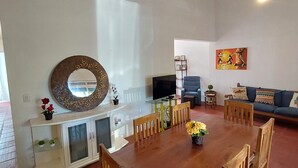 A dining area with a wooden table, chairs, a TV, and a sofa. - JUQUEHY MIDDLE OF THE BEACH, 80 METERS FROM THE SEA. (São Sebastião)