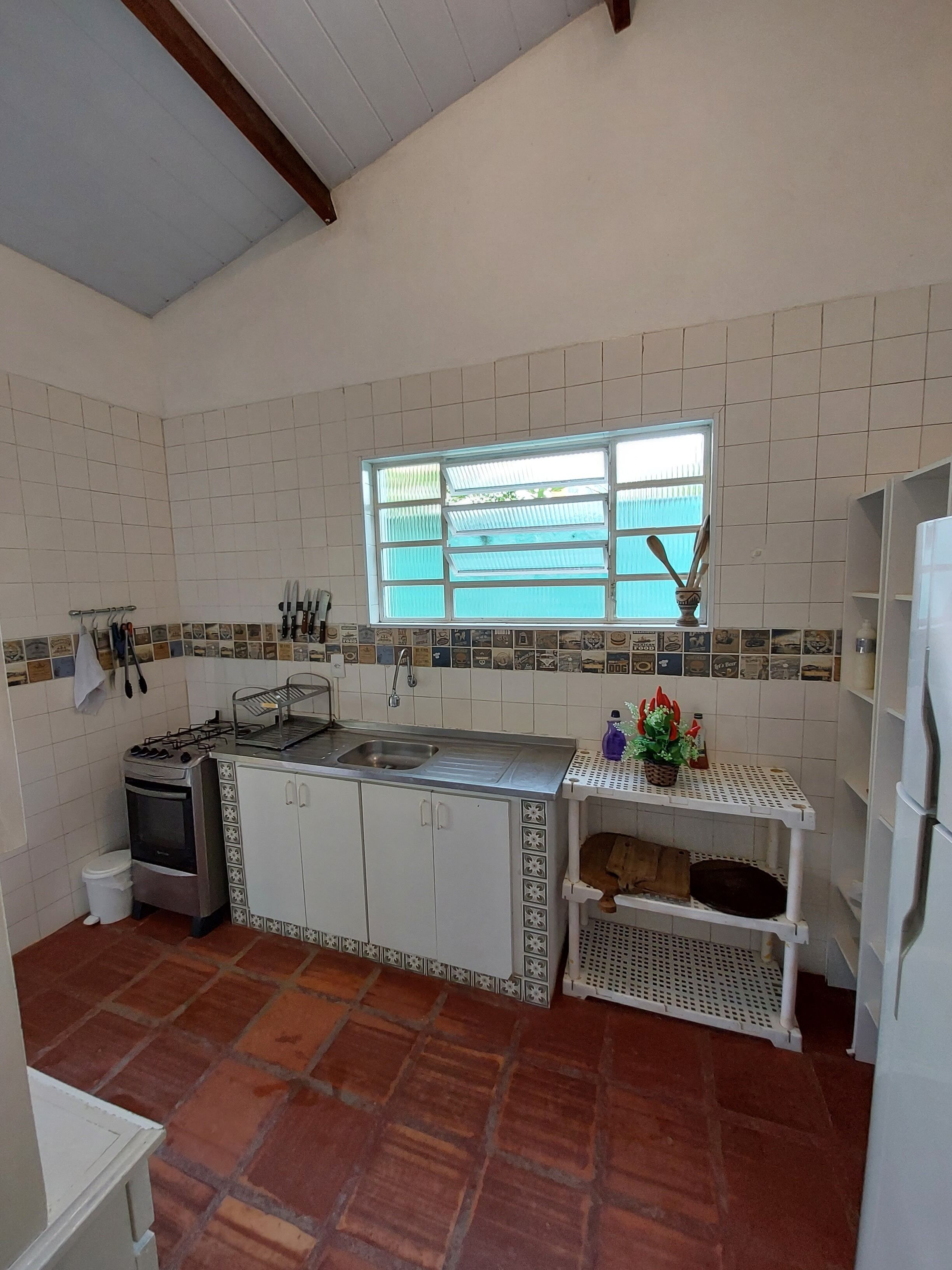 A kitchen with white cabinets, a stove, a sink, and a window with blinds.