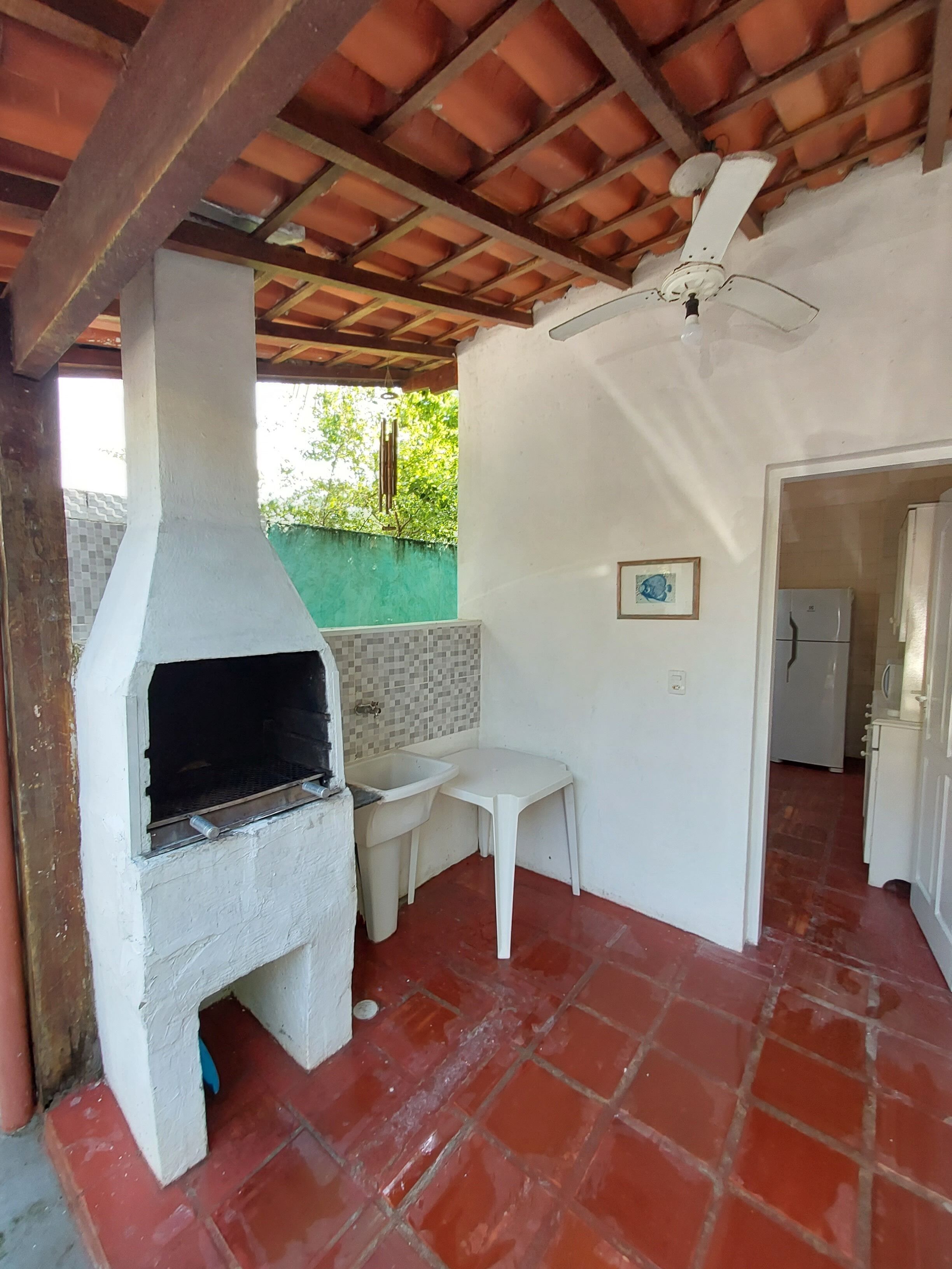 A kitchen with a built-in oven, a white sink, a small table, and a ceiling fan.