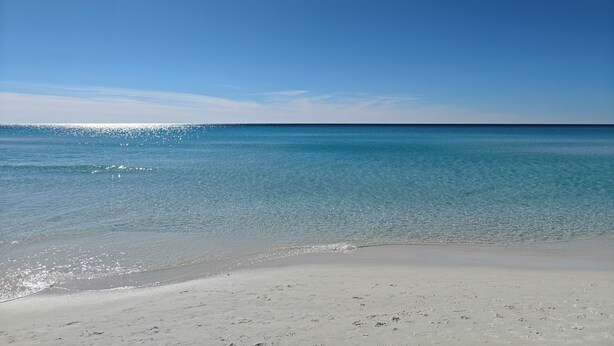 Ein Strand mit klarem, blauem Wasser und einem sandigen Ufer.