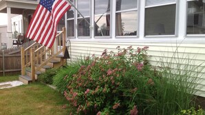 Ein Haus mit Veranda, einer Holztreppe und einer amerikanischen Flagge.