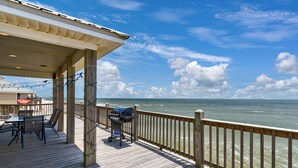 A wooden deck with a table and chairs, overlooking the ocean. - Beautiful Gulf Front home at the waves - Southern Breeze (Dauphin Island)