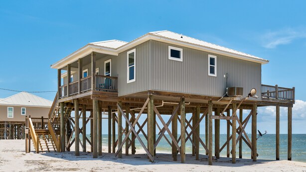 A beach house with a balcony and a wooden deck. - Beautiful Gulf Front home at the waves - Southern Breeze (Dauphin Island)