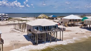 A beachfront property with multiple structures, including a main building with a balcony and several smaller buildings. - Beautiful Gulf Front home at the waves - Southern Breeze (Dauphin Island)