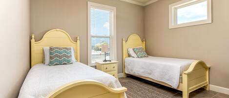 A bedroom with two beds, a ceiling fan, a window, and a nightstand.