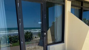 Een modern gebouw met grote glazen deuren die leiden naar een balkon met uitzicht op het strand.