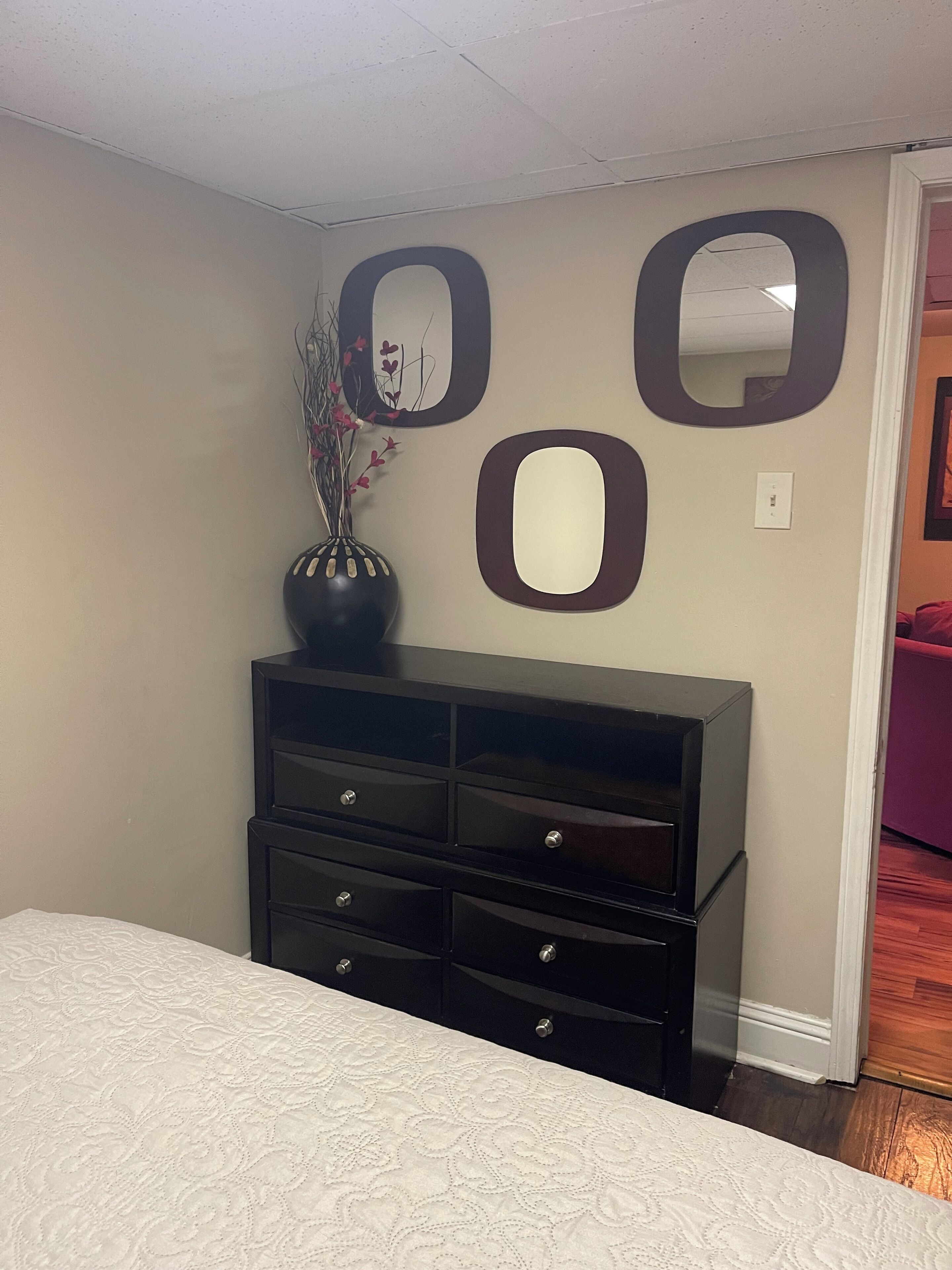 A bedroom with a bed, a dresser, and wall-mounted mirrors.