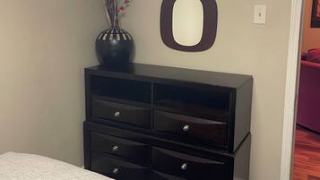 A bedroom with a bed, a dresser, and wall-mounted mirrors.