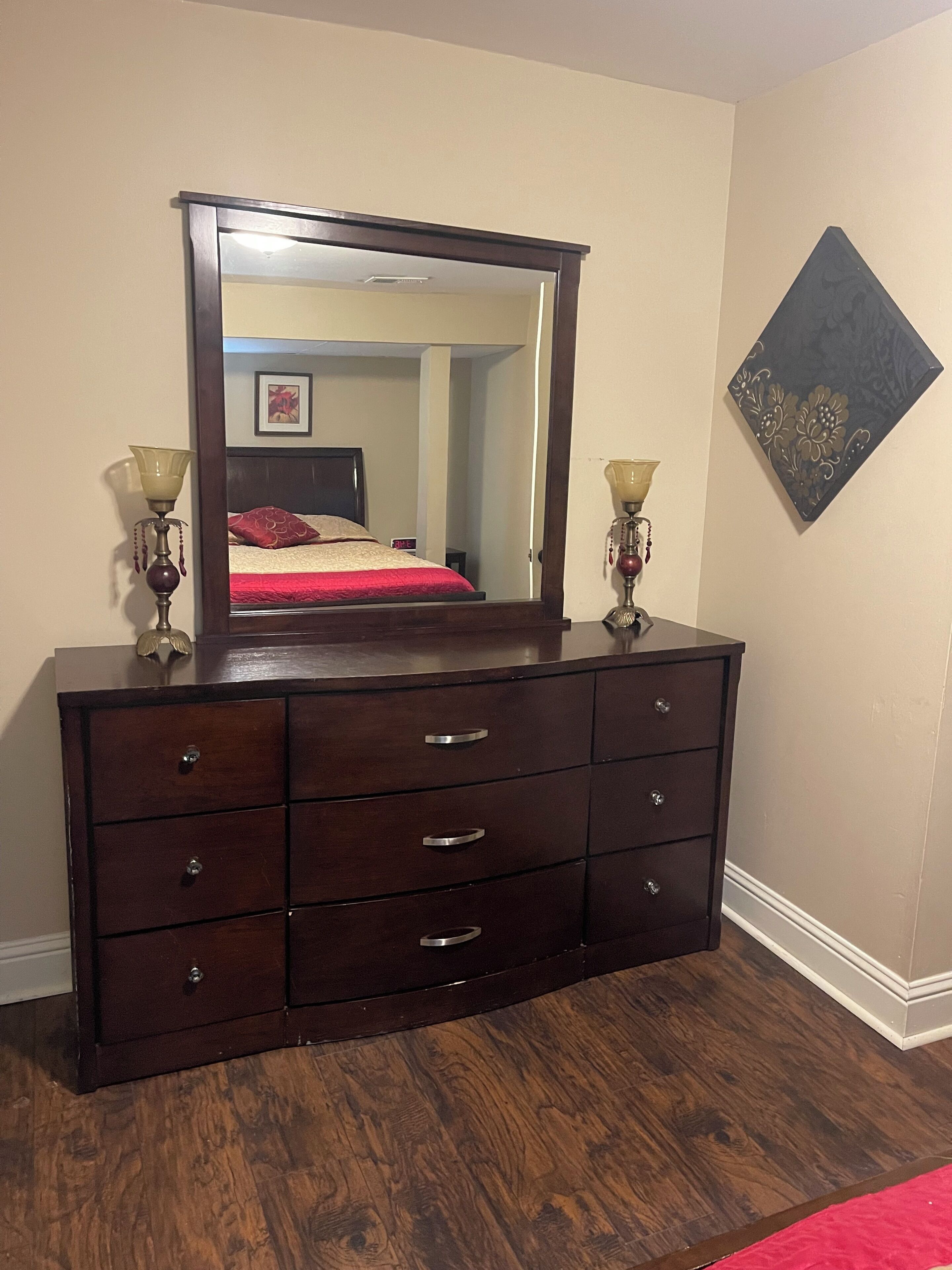 A dark wooden dresser with multiple drawers and a large mirror above it.