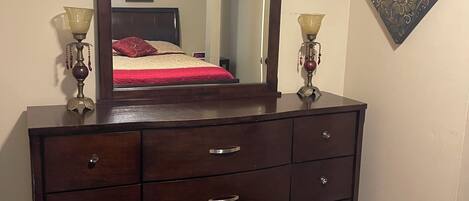 A dark wooden dresser with multiple drawers and a large mirror above it.