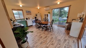 Une cuisine moderne avec un coin repas, un plancher en bois et de grandes fenêtres offrant une vue sur l’extérieur.