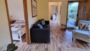 Un vaste espace de vie doté d’un plancher en bois, d’un canapé noir, d’un canapé blanc et d’une grande plante.