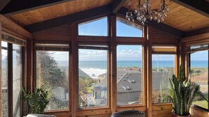 A cozy room with large windows, wooden beams, and a chandelier. - Easter Weekend Special, 20% off! Insider tip Easter egg hunt at the beach! (Manchester)