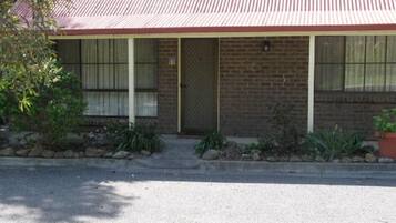 A single-story brick building with a red roof, a front door, and a small porch with steps leading up to it.