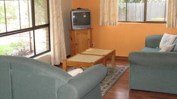 A living room with two sofas, a wooden table, and a television on a stand.