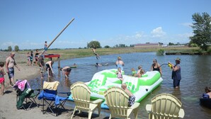Une réunion conviviale au bord de la rivière, avec des radeaux gonflables, des chaises et des personnes qui profitent de l’eau.
