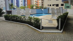 Zona de piscina con sillones blancos y un letrero que indica que está cerrada por limpieza.