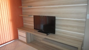 Una sala de estar moderna con un televisor de pantalla plana montado en una pared de madera con líneas horizontales.
