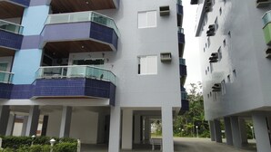 Un edificio residencial de varios pisos con balcones, fachada de azulejos y una zona de entrada cubierta.