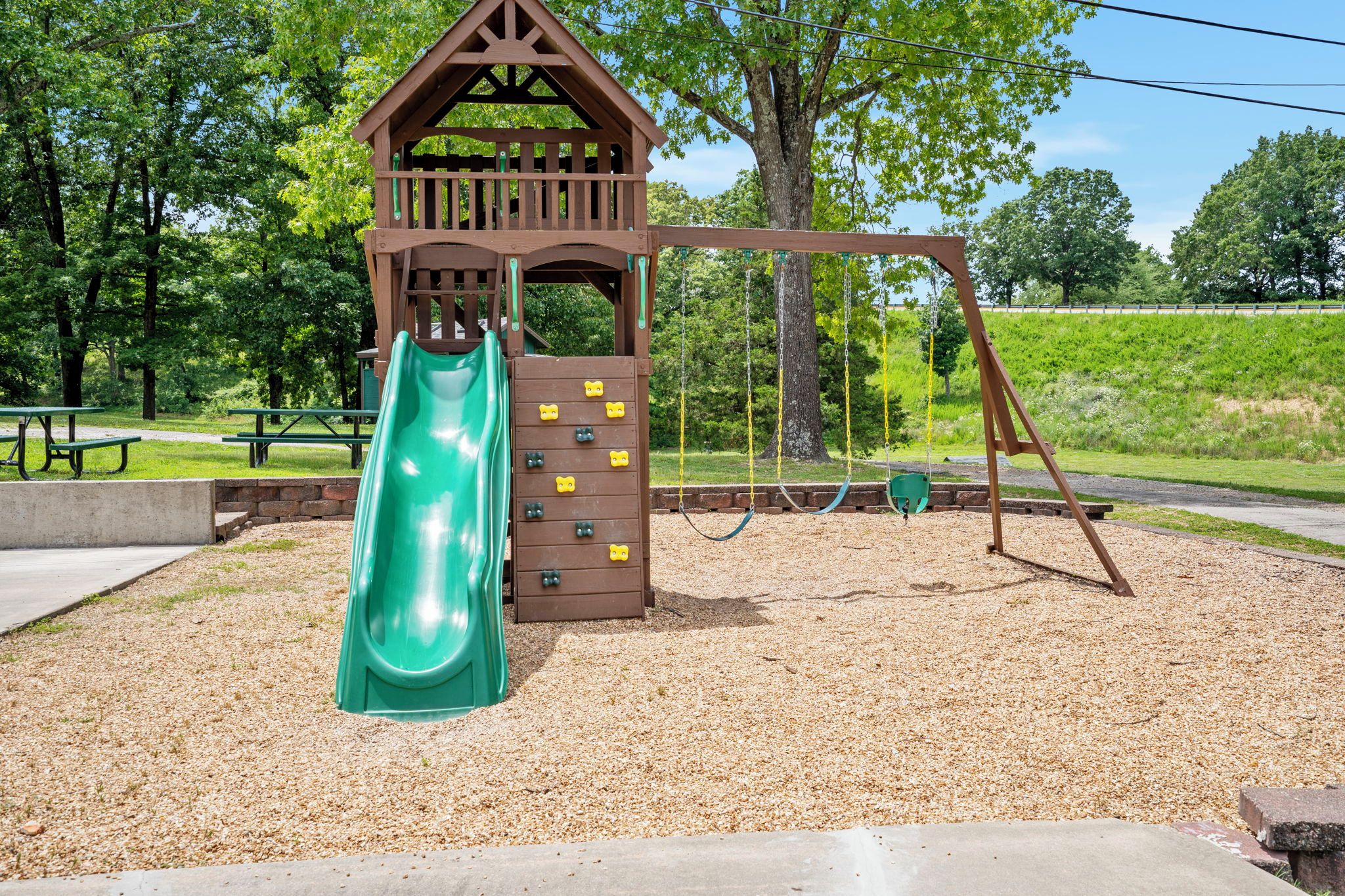 A playground with a slide, climbing wall, and swings.