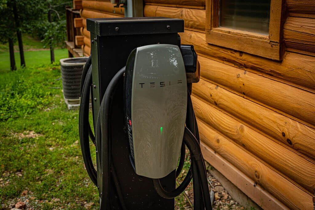 Une borne de recharge Tesla située à l’extérieur d’un chalet en bois.