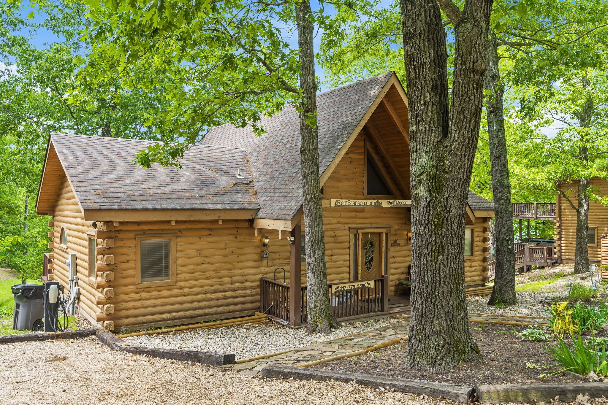 A log cabin with a sloped roof, a front porch, and a small deck area.