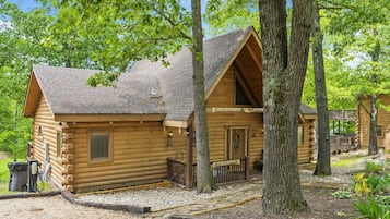 A log cabin with a sloped roof, a front porch, and a small deck area.