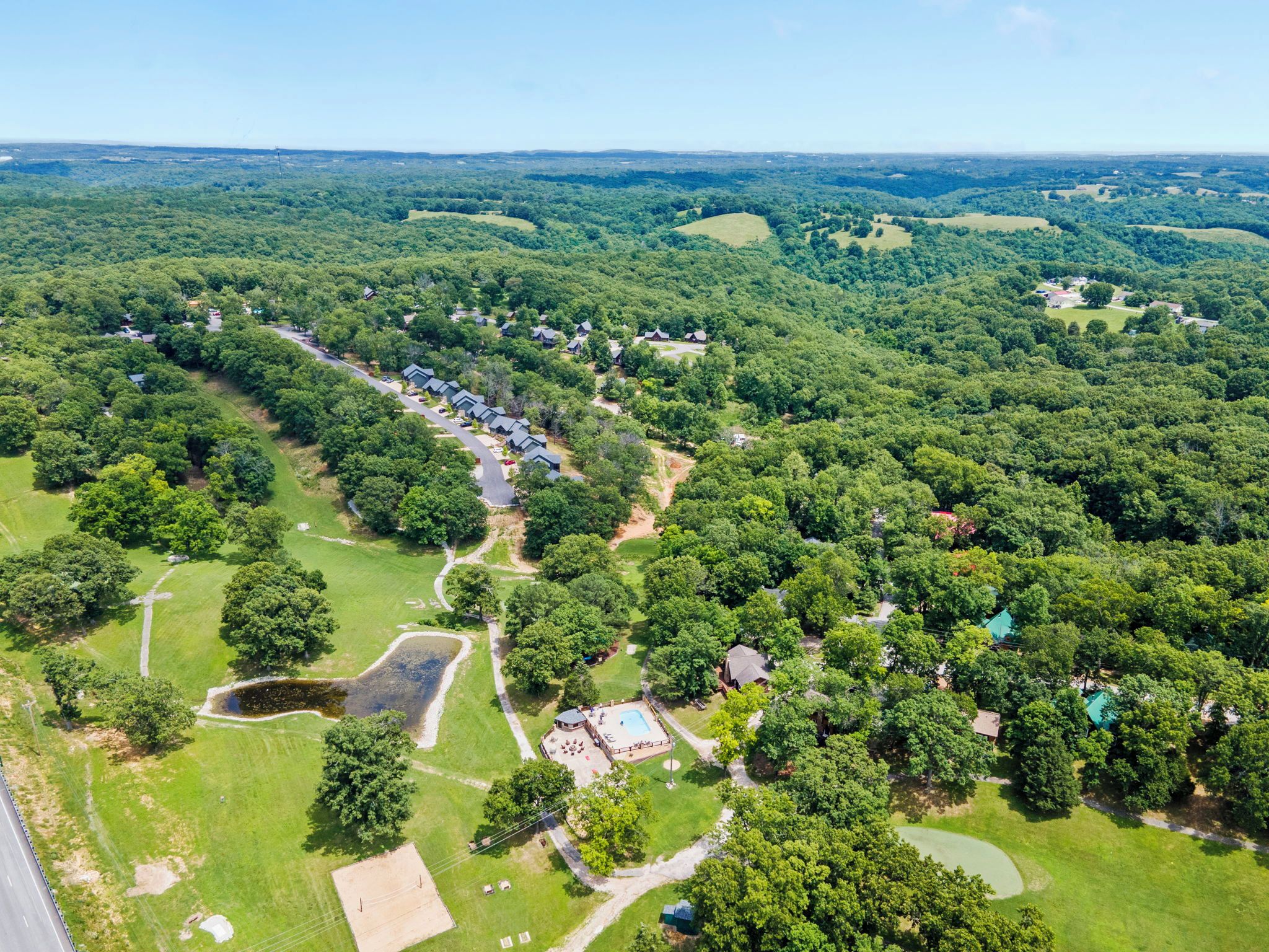 An aerial view of a residential area with houses, green spaces, and a swimming pool.