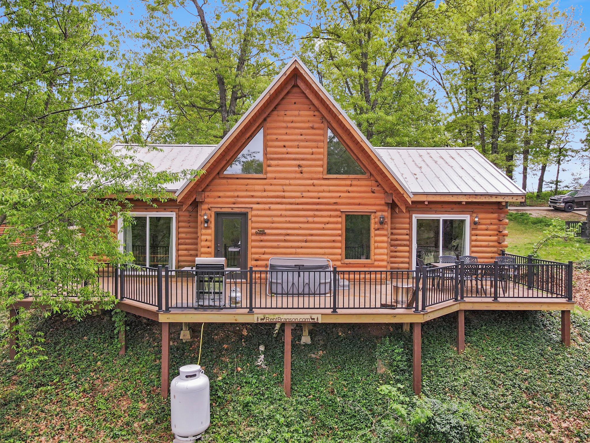 A wooden cabin with a deck, two doors, and a chimney.
