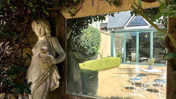 A stone statue in a garden setting with a view of a conservatory and outdoor seating area. - Kirribilli Luxury Grand Terrace House - your family oasis to explore Sydney (Sydney North)