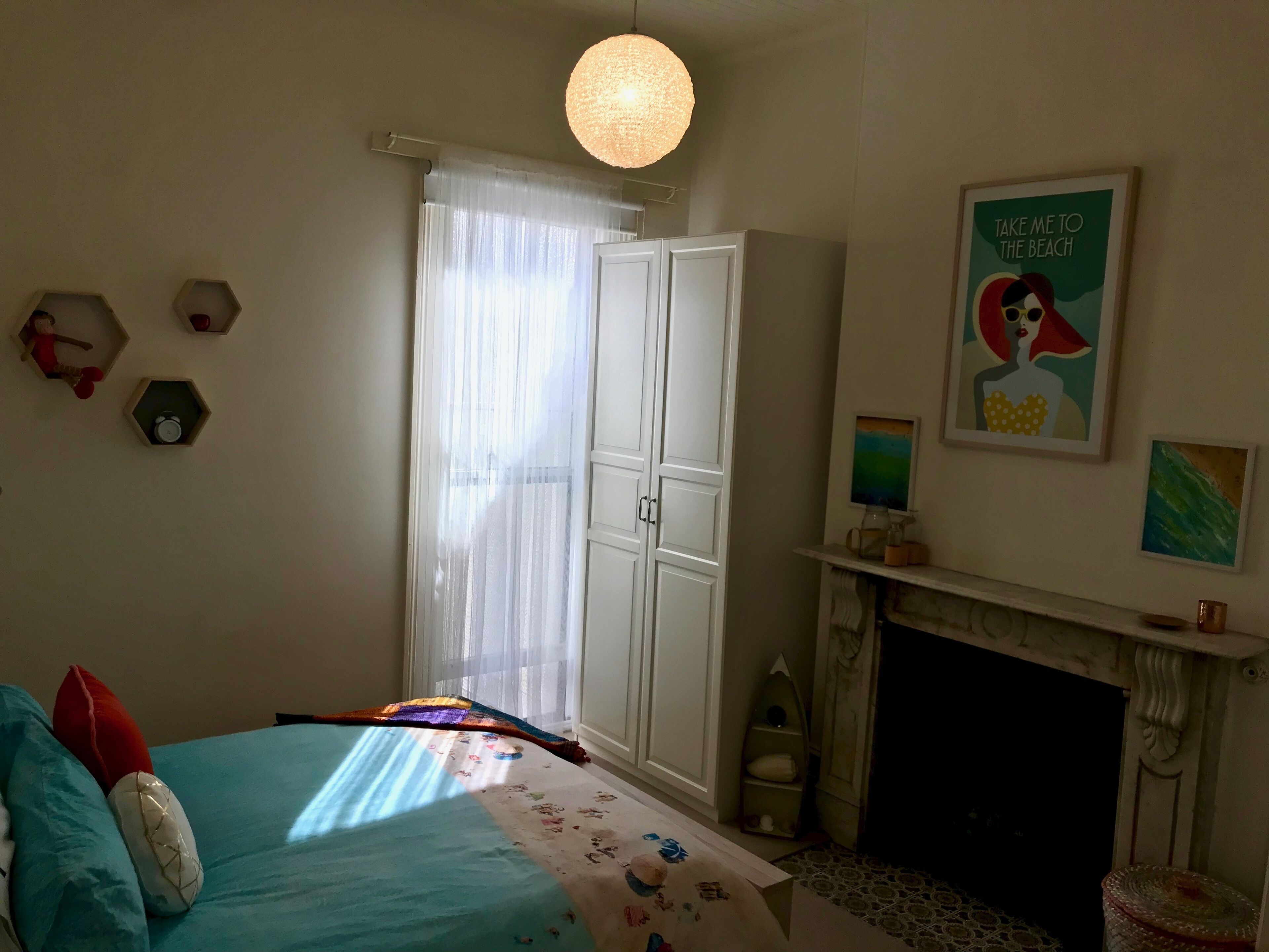 Ein Schlafzimmer mit einem Bett, einem Fenster mit Vorhängen, einem Kamin und Wanddekorationen.