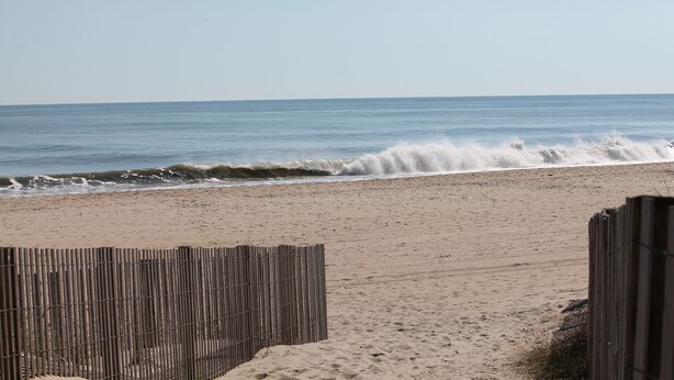Una platja amb una tanca de fusta i on les onades baten contra la riba.