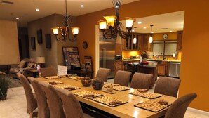 A dining area with a long table set for a meal, surrounded by chairs. - LAZY RIVER!  SLIDE and WATERFALLS!  GAMEROOM. (Palm Springs)