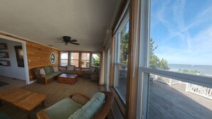 A sunlit room with a view of the sea, furnished with wicker furniture and a ceiling fan. - Relax big in a small beach town! (Milford)