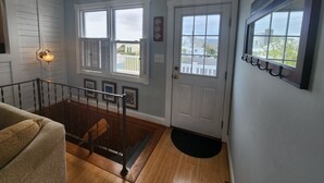 A staircase leading to a landing with a door, a light fixture, and a view of the outside. - Relax big in a small beach town! (Milford)