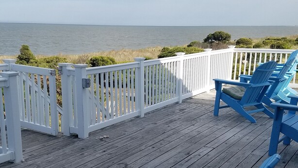 A wooden deck with blue Adirondack chairs and a white railing overlooking the ocean. - Relax big in a small beach town! (Milford)