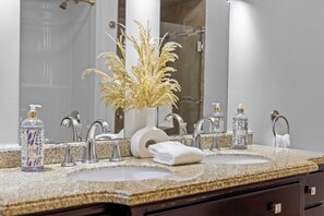 Casa de banho com duas pias, um espelho e uma planta decorativa.